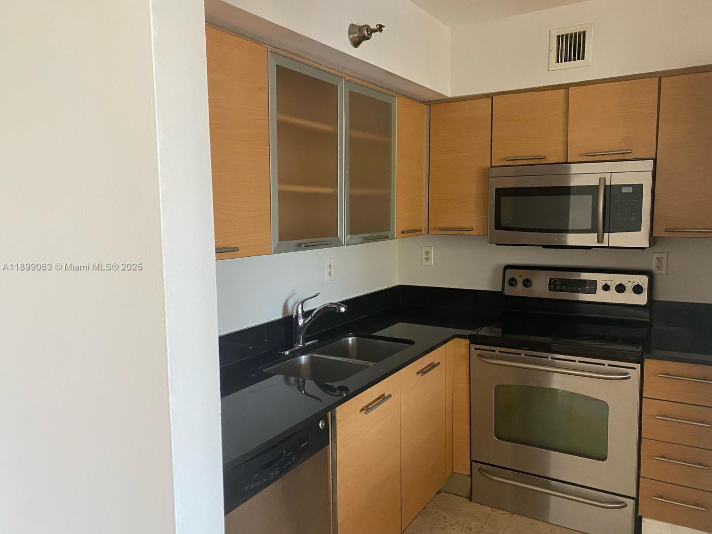 3300 Northeast 191st Street, Unit 416 Aventura, FL 33180 - Photo 4 of 26 a kitchen with granite countertop a stove and a microwave