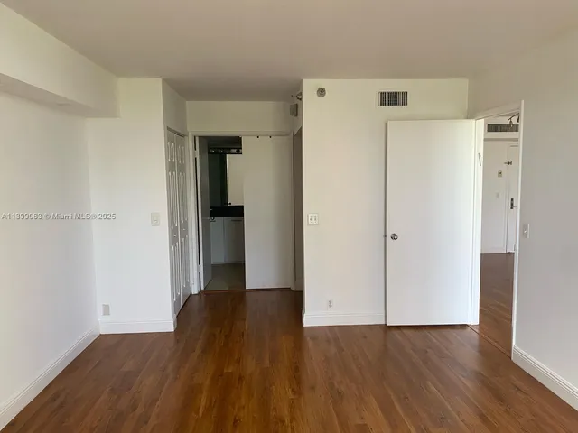 a view of a room with wooden floor and a refrigerator