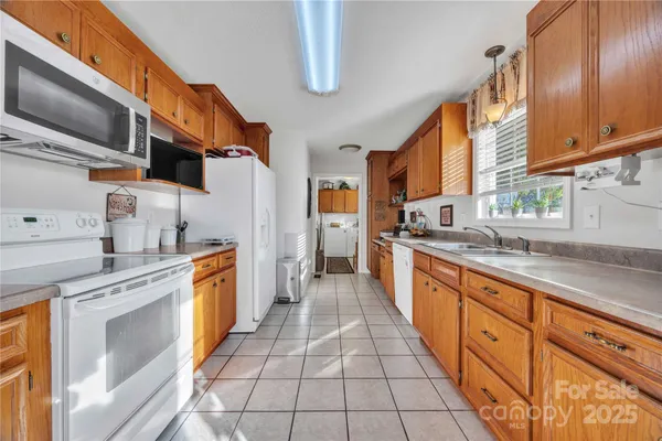 a large kitchen with stainless steel appliances granite countertop a stove a sink and a microwave