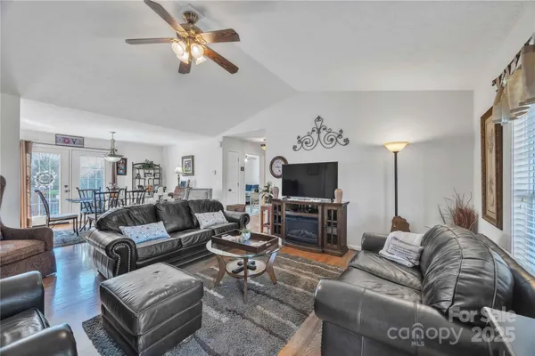 a living room with furniture a flat screen tv and kitchen view
