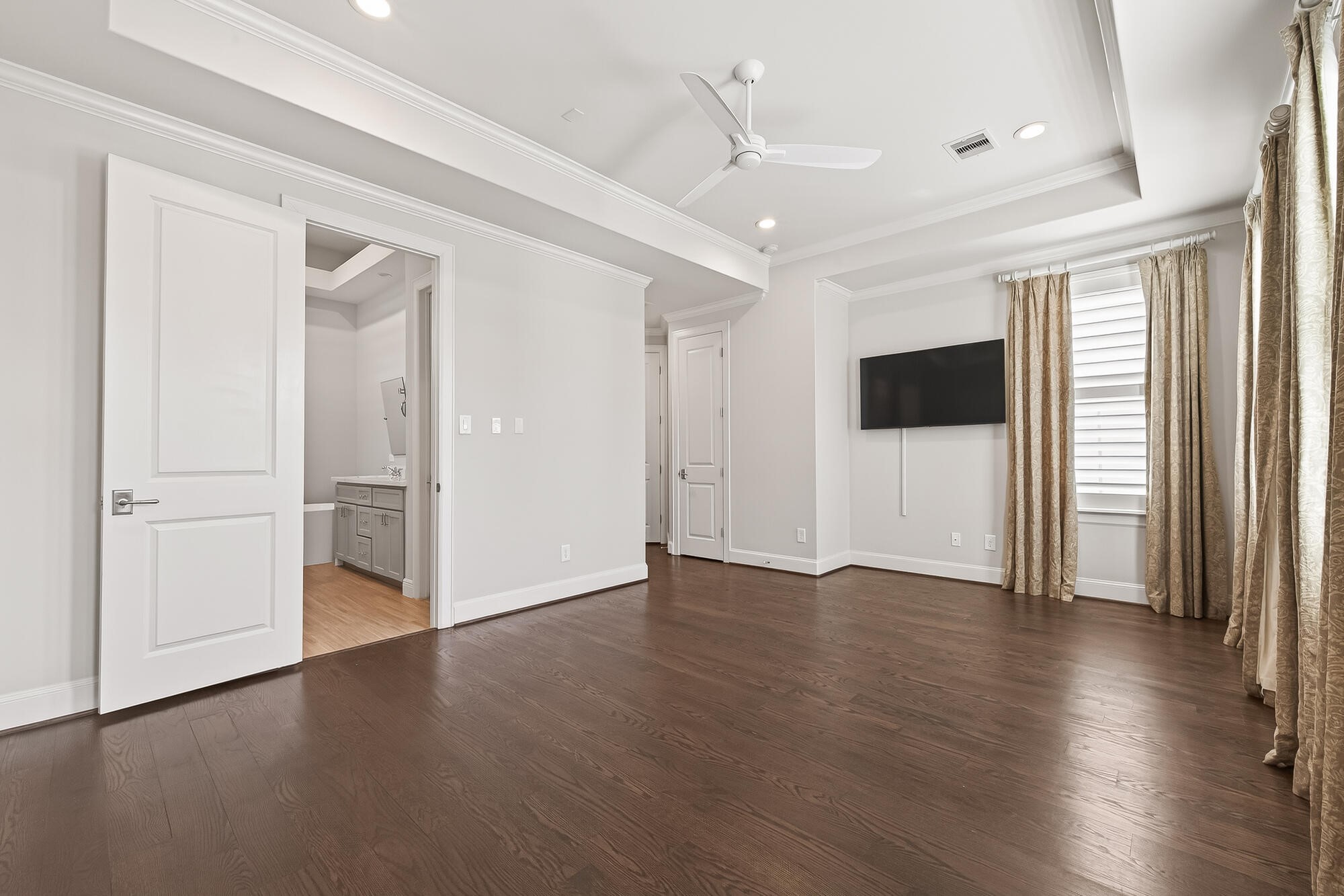 122 Gateway Park Place Spring, TX 77380 - Photo 29 of 44 Spacious primary bedroom with tray ceiling, upgraded wood floors, and bright windows steps from the bath.