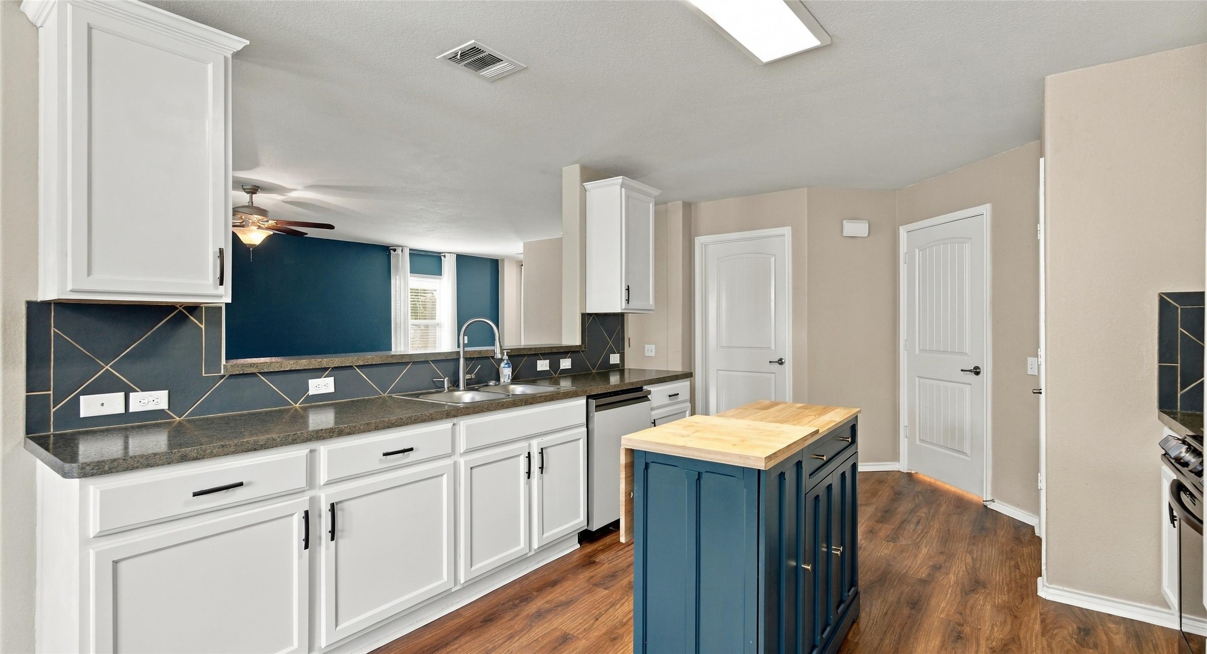 7224 Crestone Road Austin, TX 78744 - Photo 14 of 33 Rich wood flooring anchors this well-equipped kitchen containing built-in cabinets and a functional central island.