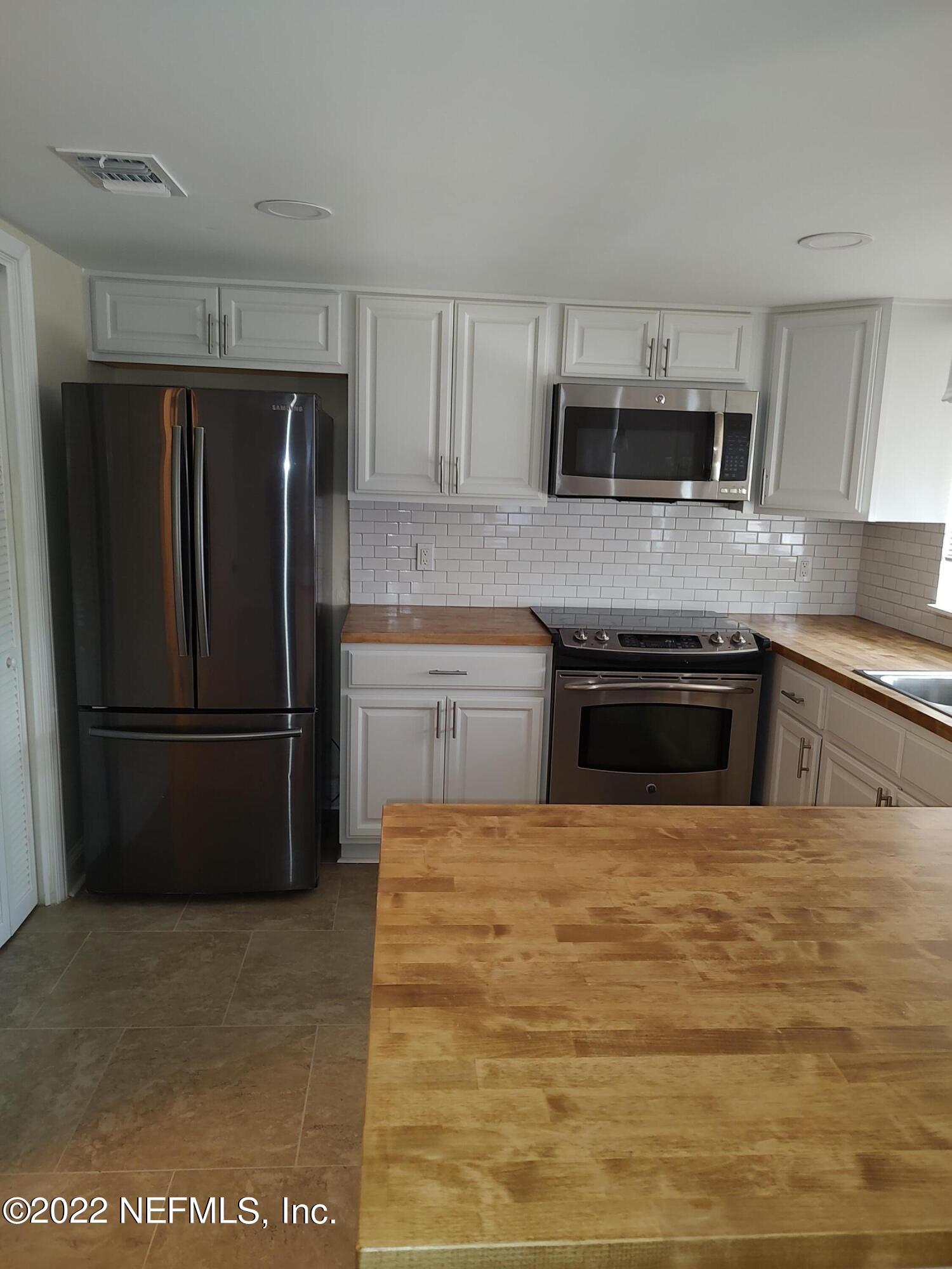 3517 Peeler Road, Unit 13 Jacksonville, FL 32277 - Photo 12 of 31 a kitchen with stainless steel appliances granite countertop a refrigerator a stove a sink and a microwave
