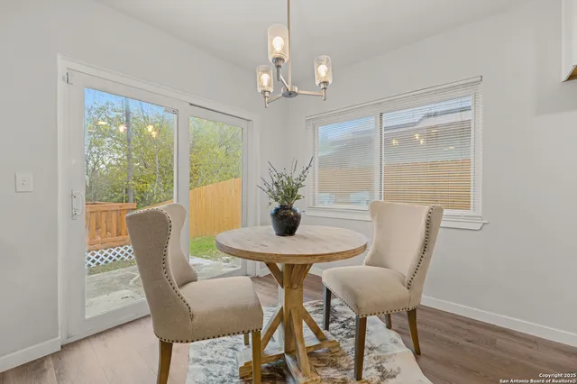 a dining room with furniture wooden floor a potted plant and a chandelier