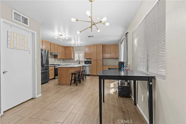 a kitchen with stainless steel appliances a table chairs refrigerator and cabinets