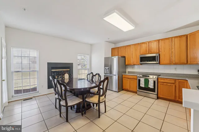 a kitchen with stainless steel appliances a stove a sink a microwave a dining table and chairs