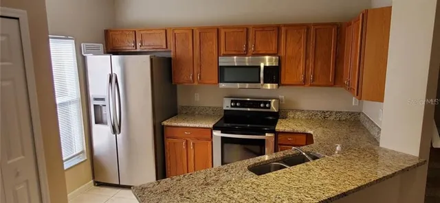 a kitchen with stainless steel appliances granite countertop a refrigerator stove and microwave