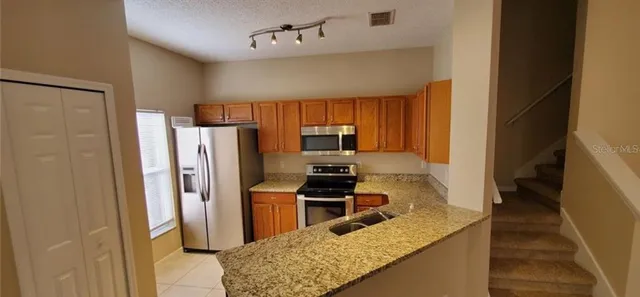 a kitchen with stainless steel appliances granite countertop a refrigerator a stove and a sink
