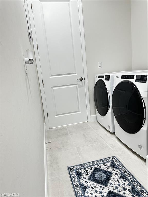 7135 Cayo Coco Lane Naples, FL 34113 - Photo 23 of 41 Laundry room featuring washer and clothes dryer and light tile patterned floors