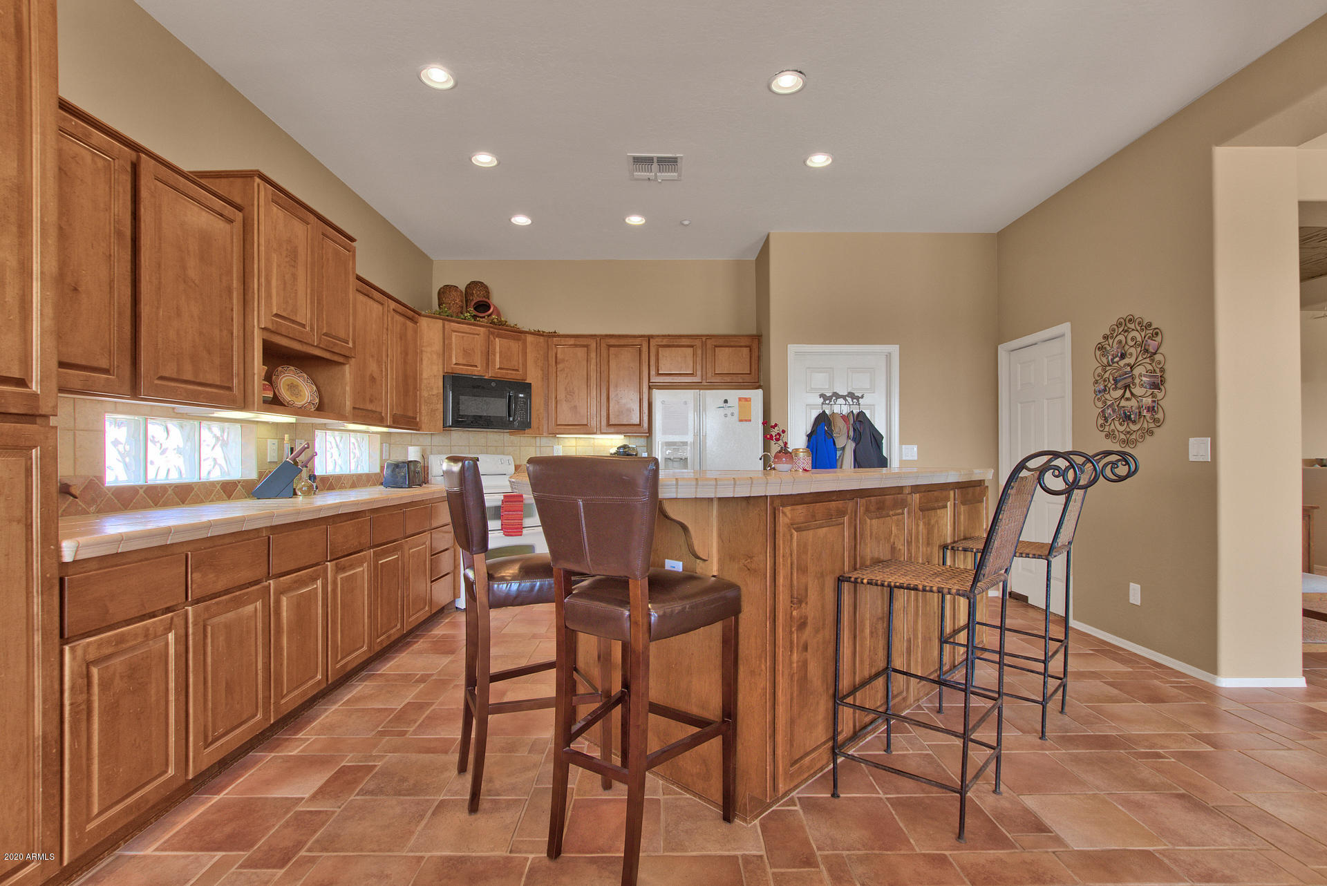 42045 North Crooked Stick Road Anthem, AZ 85086 - Photo 18 of 37 a kitchen with stainless steel appliances kitchen island granite countertop a table chairs sink refrigerator and cabinets