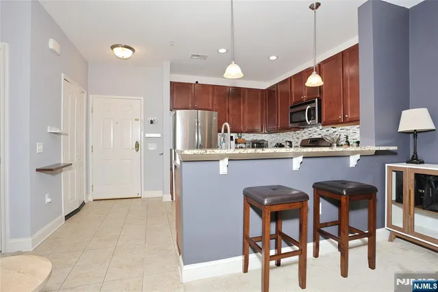 a kitchen with stainless steel appliances granite countertop a table chairs refrigerator and sink