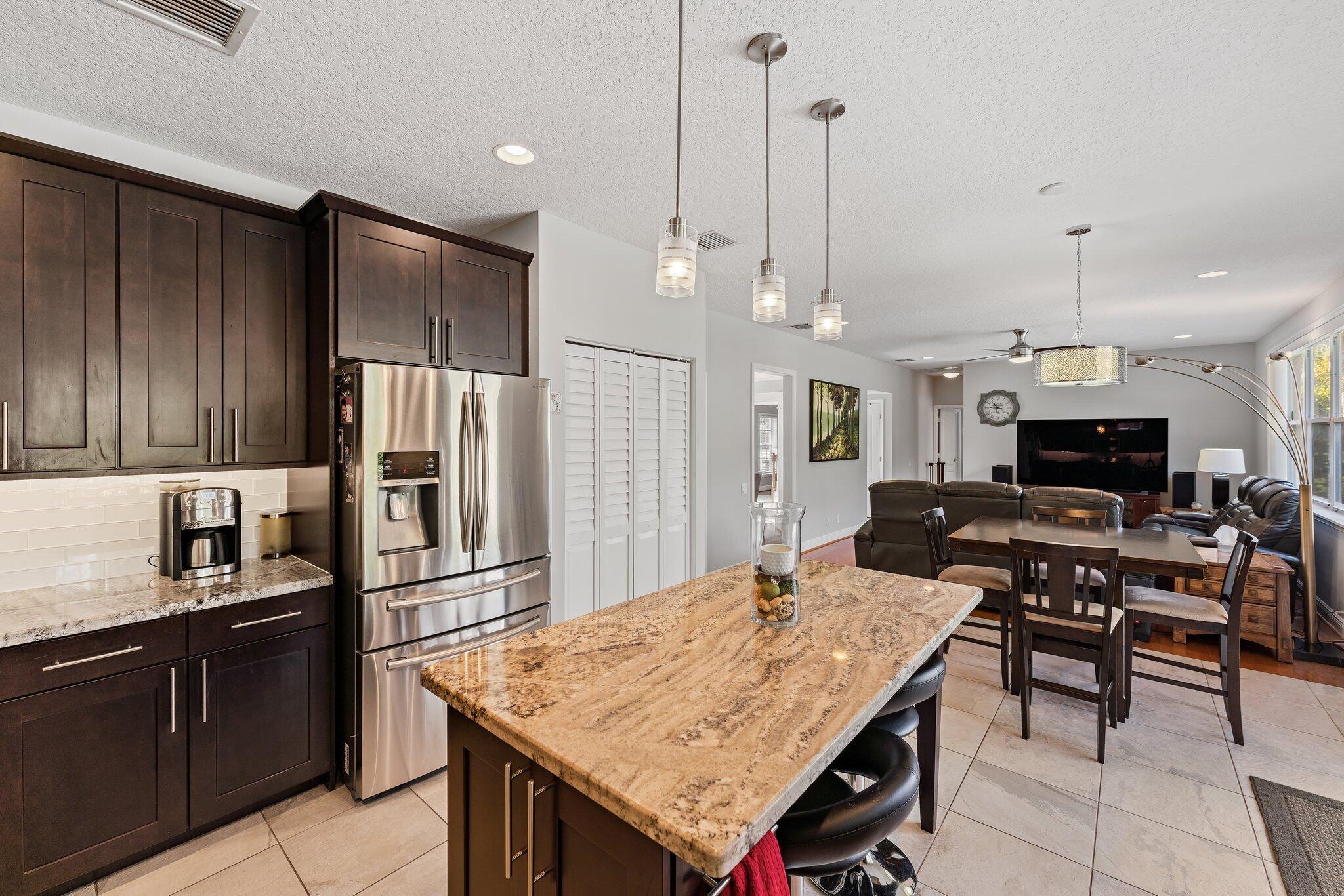 203 Anhinga Lane Jupiter, FL 33458 - Photo 13 of 63 a kitchen with stainless steel appliances kitchen island granite countertop a table chairs and a refrigerator