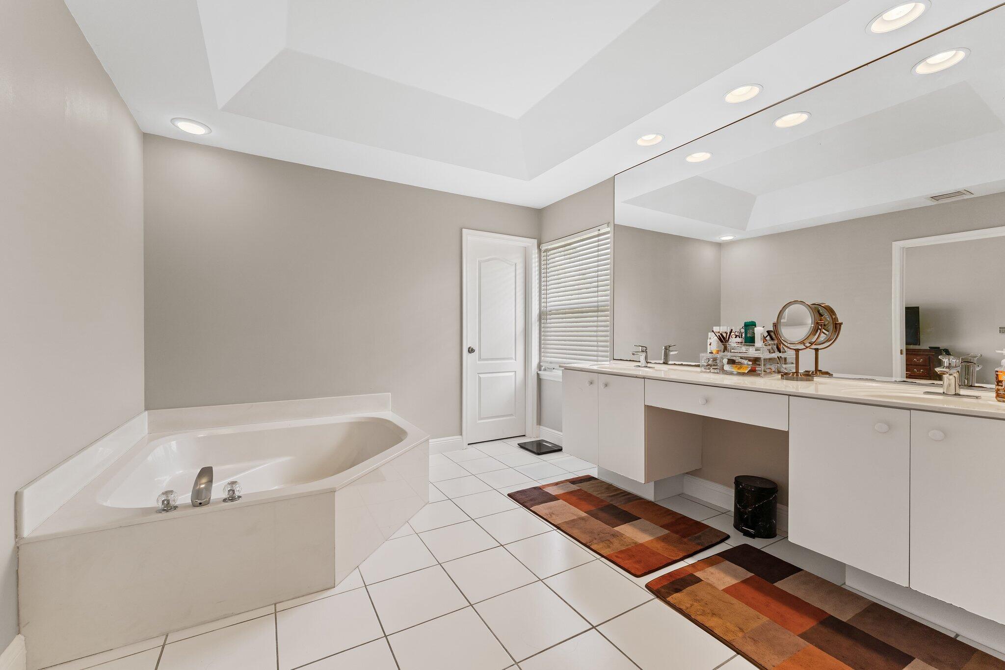203 Anhinga Lane Jupiter, FL 33458 - Photo 30 of 63 a bathroom with a bathtub sink vanity and mirror