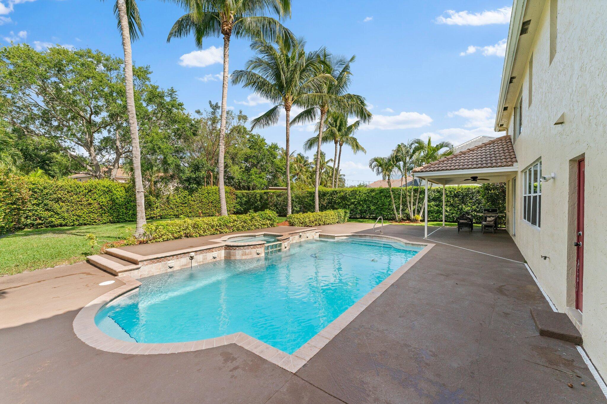 203 Anhinga Lane Jupiter, FL 33458 - Photo 47 of 63 a view of a swimming pool with a yard and palm trees
