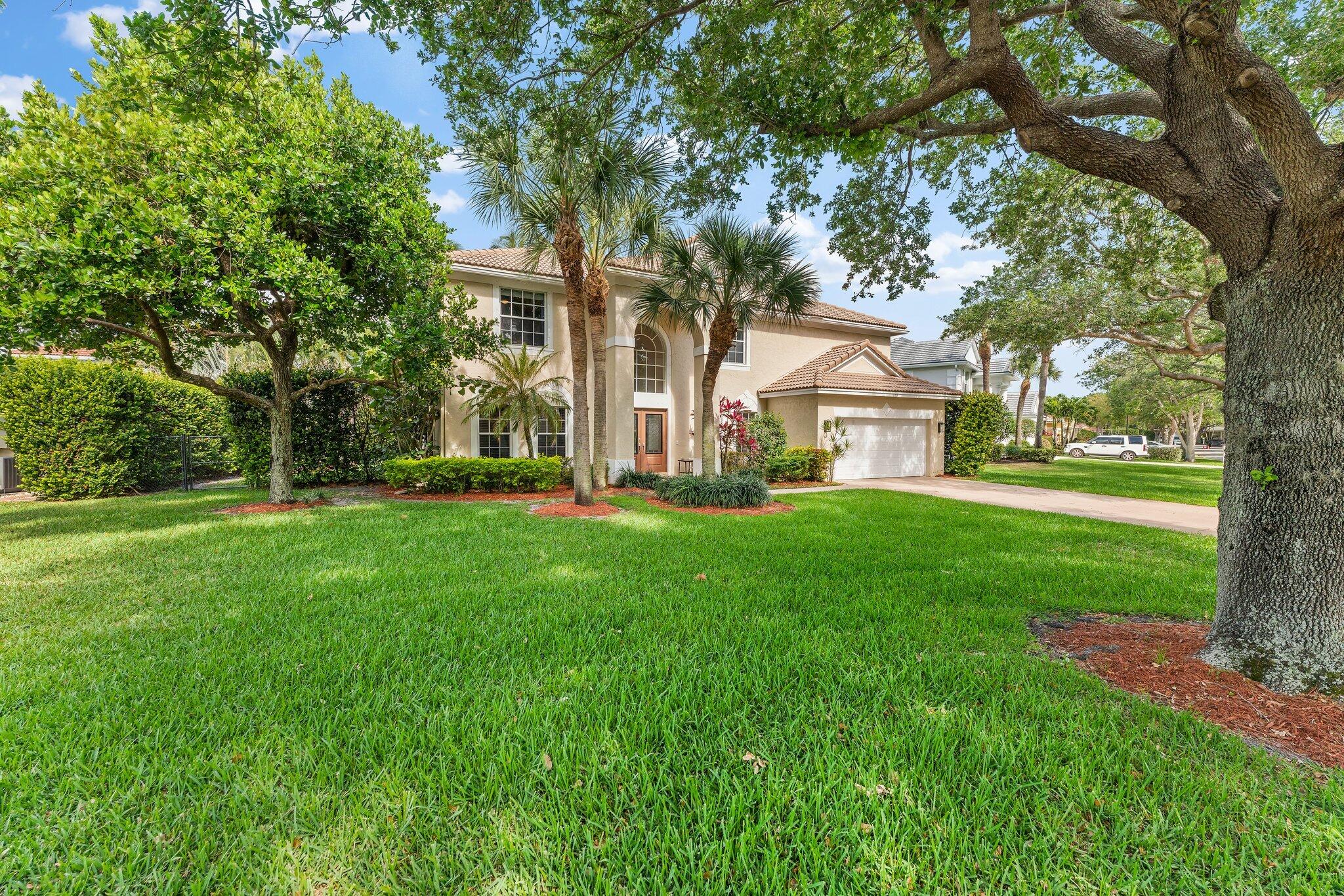 203 Anhinga Lane Jupiter, FL 33458 - Photo 60 of 63 a view of a white house in front of a big yard with large trees