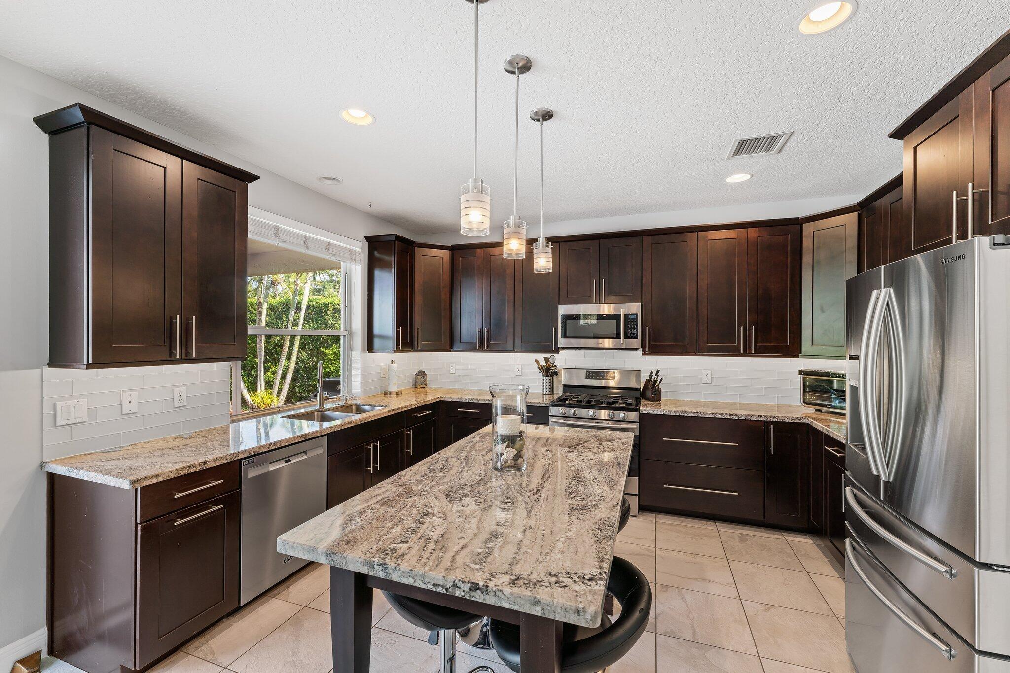 203 Anhinga Lane Jupiter, FL 33458 - Photo 8 of 63 a kitchen with granite countertop stainless steel appliances and wooden cabinets