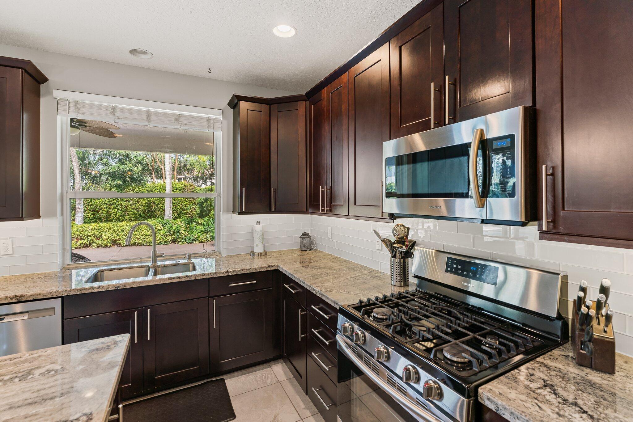 203 Anhinga Lane Jupiter, FL 33458 - Photo 9 of 63 a kitchen with stainless steel appliances a sink stove and microwave