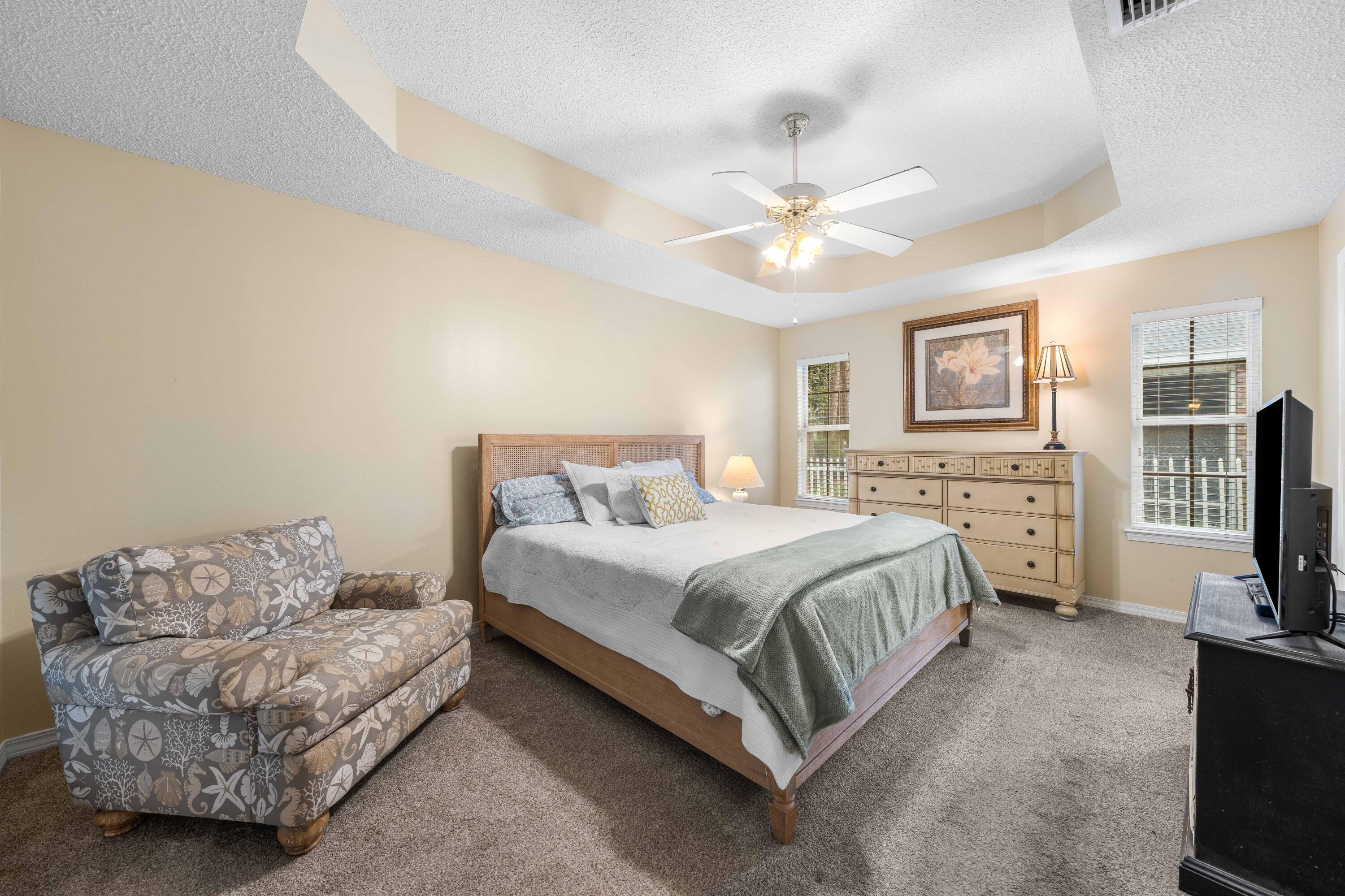 328 Bay Tree Drive Miramar Beach, FL 32550 - Photo 21 of 49 a spacious bedroom with a bed a couch and a flat tv screen on the dresser