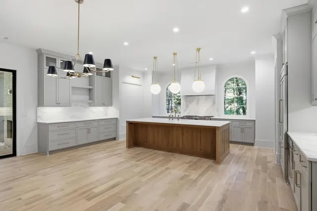 a large kitchen with a large counter top a sink stainless steel appliances and cabinets