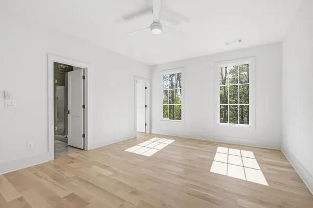 a view of empty room with wooden floor and fan