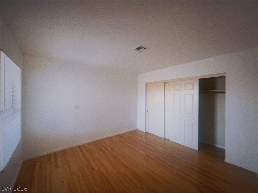 6250 West Flamingo Road, Unit 60 Las Vegas, NV 89103 - Photo 11 of 23 An empty room offers warm wood floors and ample closet space with sliding doors.