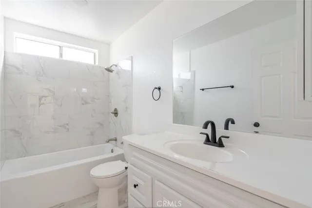 a bathroom with a sink a toilet a mirror a bathtub and shower