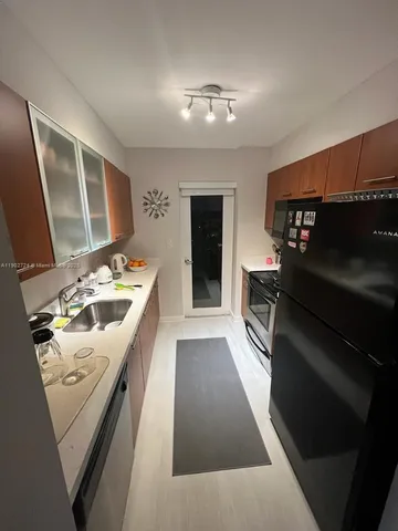 a kitchen with stainless steel appliances kitchen island granite countertop a refrigerator stove and sink