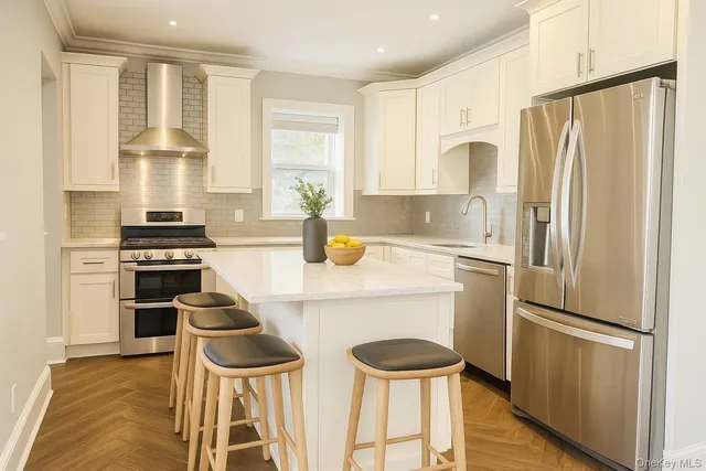 a kitchen with a refrigerator a stove and white cabinets with wooden floor