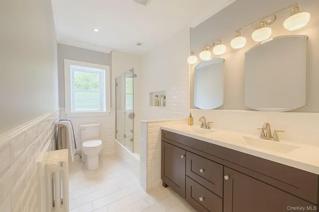 a bathroom with a double vanity sink mirror and toilet