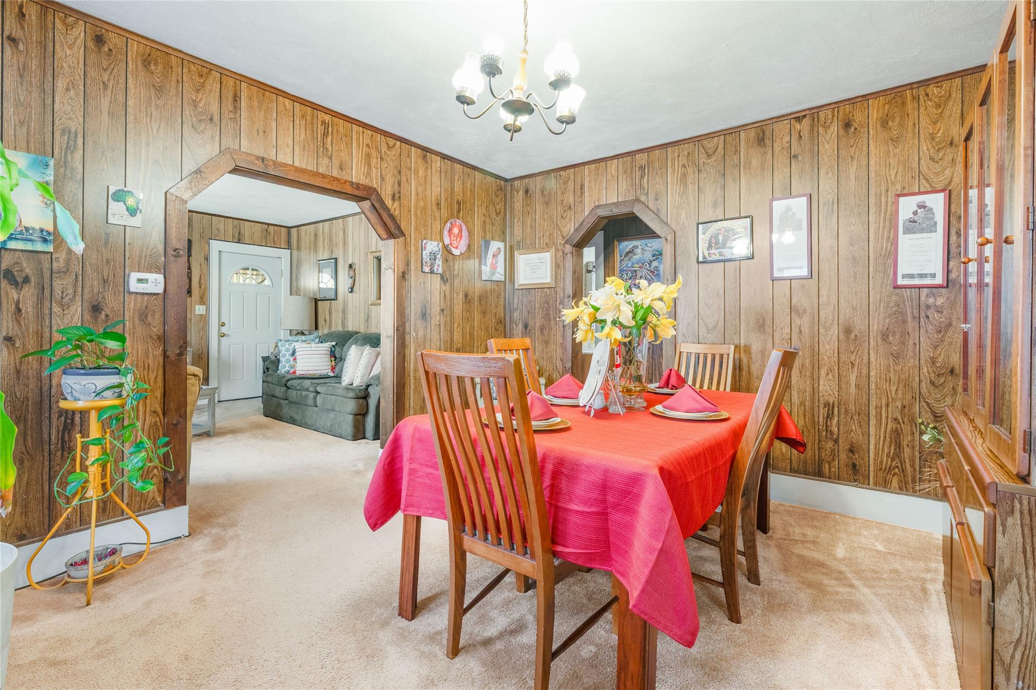 17 Lawrence Road Poughkeepsie, NY 12601 - Photo 5 of 17 Carpeted dining area featuring arched walkways, wooden walls, and a notable chandelier