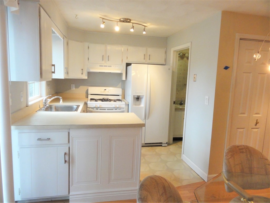 1955 Middlesex Street, Unit E Lowell, MA 01851 - Photo 4 of 20 a kitchen with a refrigerator a sink and cabinets