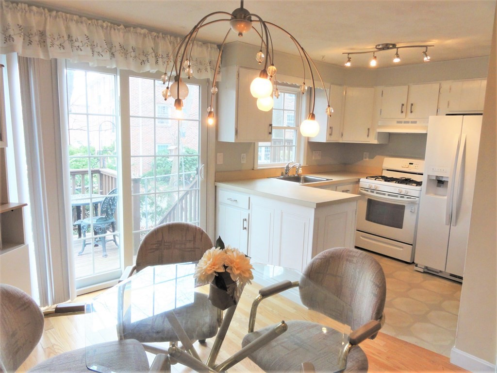 1955 Middlesex Street, Unit E Lowell, MA 01851 - Photo 6 of 20 a kitchen with a stove a refrigerator a sink dishwasher a dining table and chairs with wooden floor
