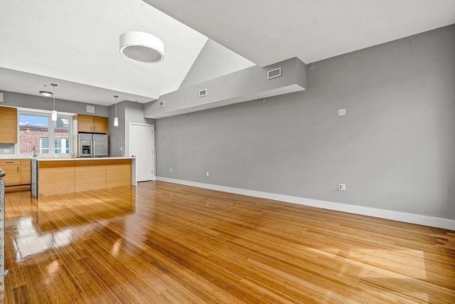 a view of kitchen and empty room with wooden floor