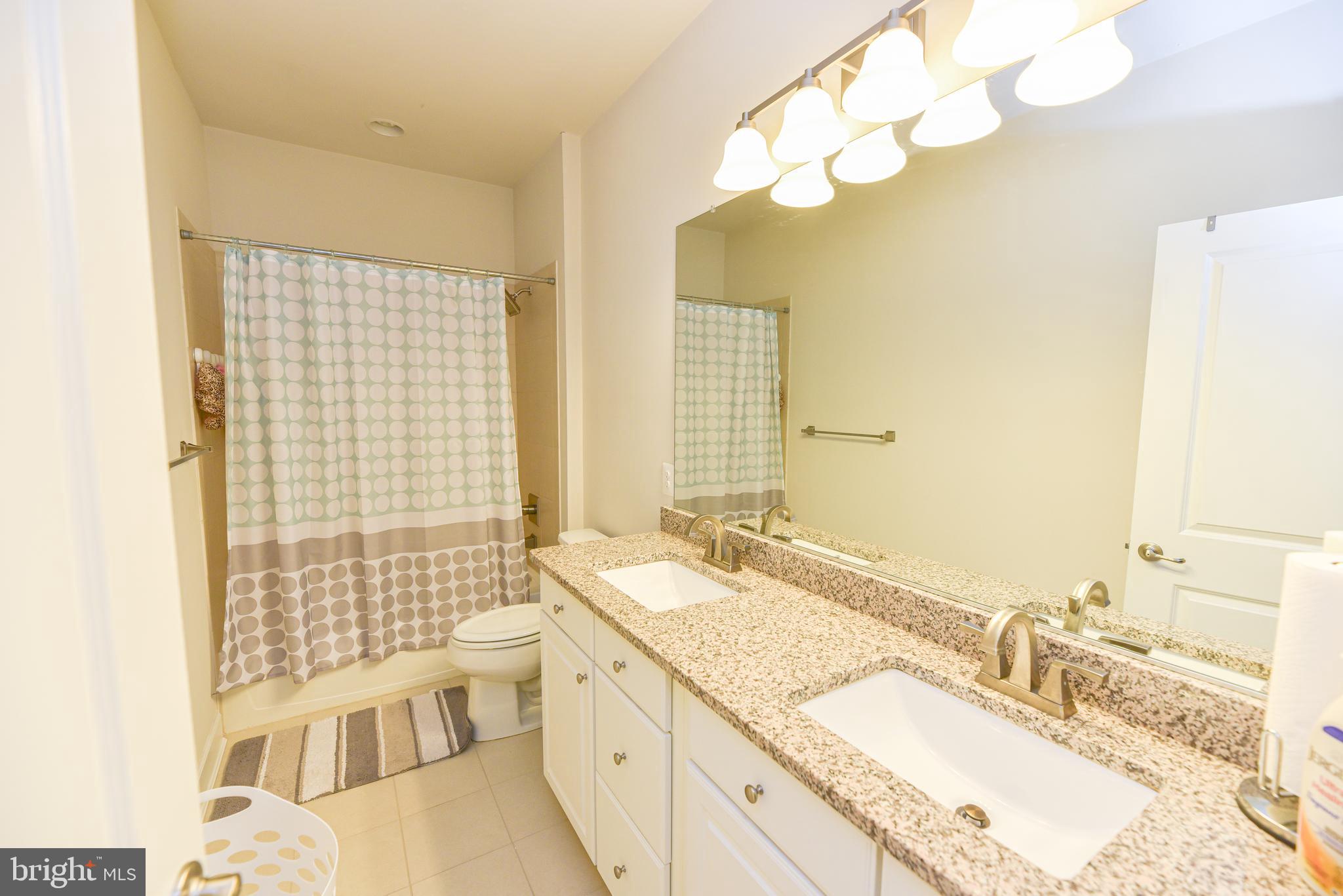 22379 Grebe Lane Ocean View, DE 19970 - Photo 34 of 41 a bathroom with a granite countertop double vanity sink a mirror and a bathtub