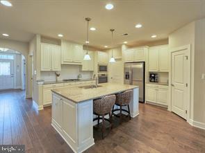 22379 Grebe Lane Ocean View, DE 19970 - Photo 5 of 41 a kitchen with kitchen island a refrigerator a oven a sink and white cabinets with wooden floor