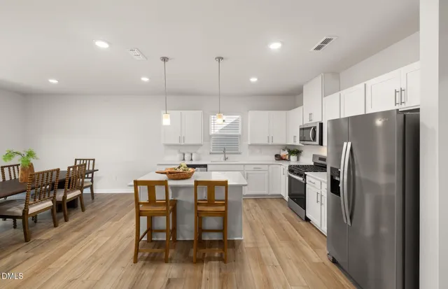 a kitchen with stainless steel appliances granite countertop a refrigerator a sink dishwasher a stove and white cabinets