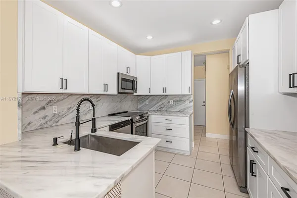 a kitchen with stainless steel appliances granite countertop a sink and a refrigerator