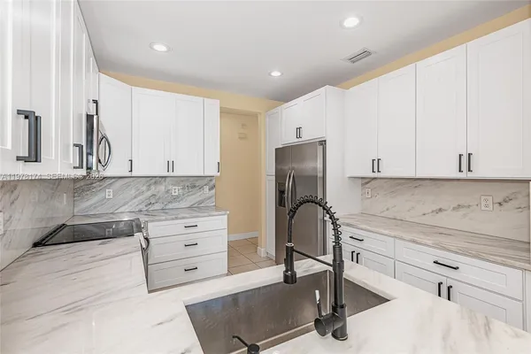 a kitchen with granite countertop white cabinets and appliances