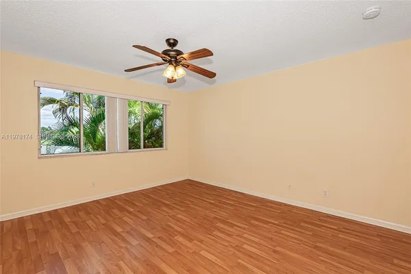 a view of empty room with wooden floor and fan