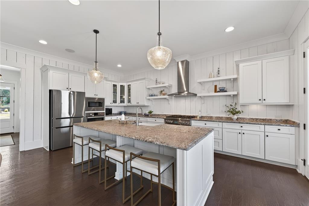 554 Gables Run Milton, GA 30004 - Photo 8 of 47 a kitchen with stainless steel appliances granite countertop a stove a sink a kitchen island a refrigerator a stove a dining table and chairs with wooden floor