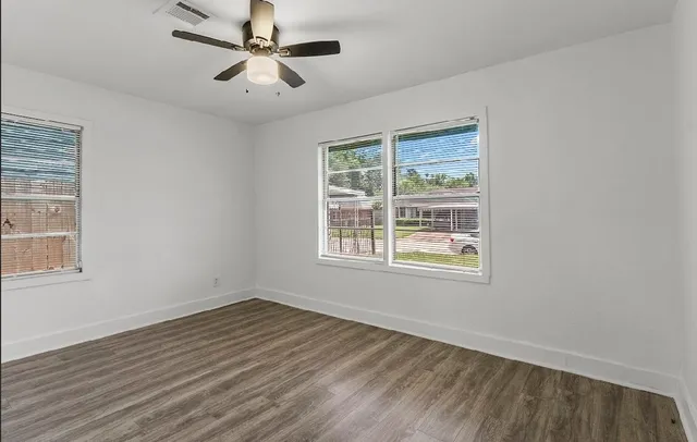 a view of an empty room with wooden floor and a window
