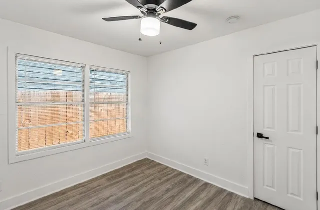 a view of an empty room with wooden floor and a window