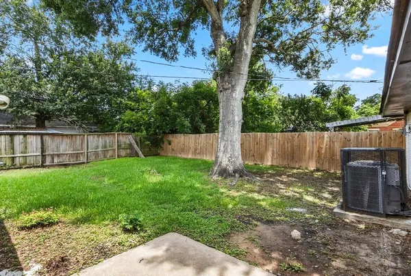 a view of a backyard with a tree and wooden fence
