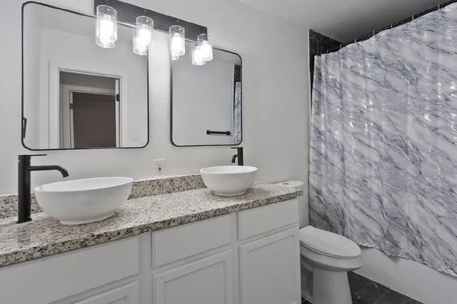 a bathroom with a granite countertop sink a toilet and a mirror