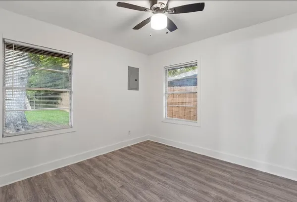 a view of an empty room with wooden floor and a window