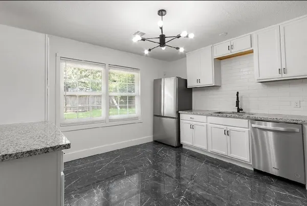 a kitchen with stainless steel appliances granite countertop a stove a sink dishwasher and a refrigerator