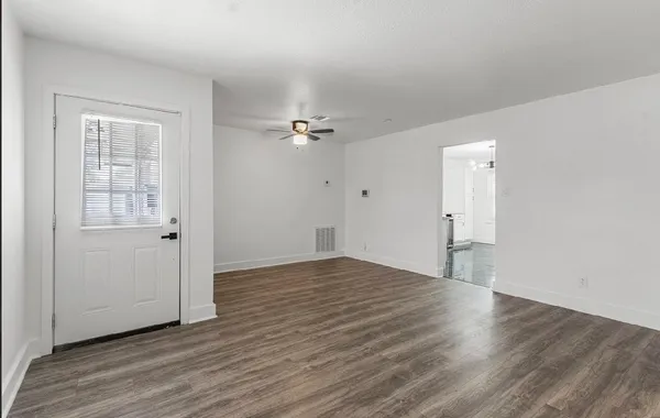 an empty room with wooden floor and windows