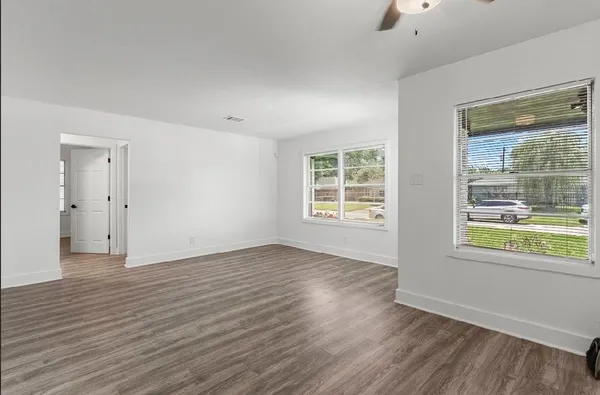 an empty room with wooden floor and windows