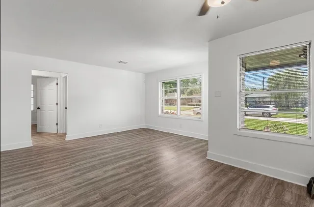 an empty room with wooden floor and windows
