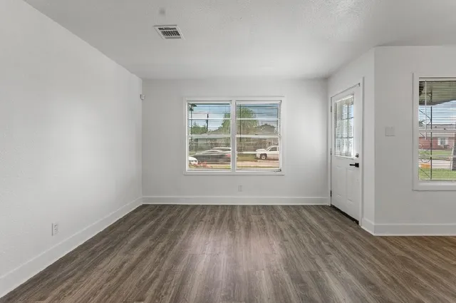 an empty room with wooden floor and windows